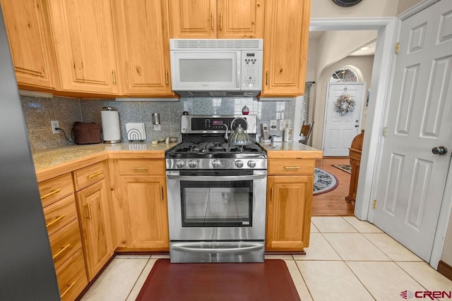 1060 Alta Vista Dr, Craig, CO 81625 - kitchen with white microwave, gas stove, light tile patterned flooring, and backsplash