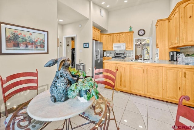 1060 Alta Vista Dr, Craig, CO 81625 - kitchen featuring stainless steel appliances, backsplash, a peninsula, light tile patterned floors, and a towering ceiling