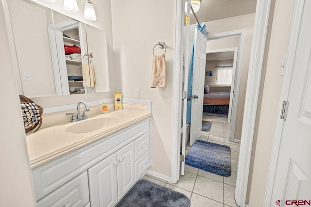 1060 Alta Vista Dr, Craig, CO 81625 - bathroom with tile patterned flooring, vanity, baseboards, connected bathroom, and a walk in closet