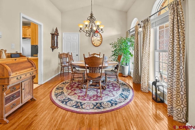 1060 Alta Vista Dr, Craig, CO 81625 - dining room featuring light wood-type flooring, vaulted ceiling, a chandelier, and baseboards