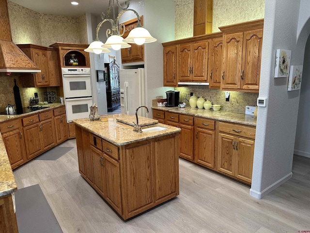 20 Meadow Ln, Monte Vista, CO 81144 - kitchen with white appliances, decorative backsplash, brown cabinetry, a kitchen island with sink, and light wood finished floors