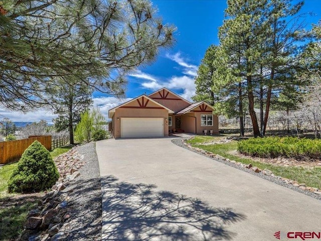 338 Escobar Ave, Pagosa Springs, CO 81147 - view of front of house with fence, an attached garage, driveway, and stucco siding