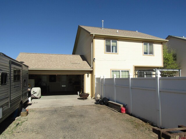 back of house featuring fence, driveway, and a garage