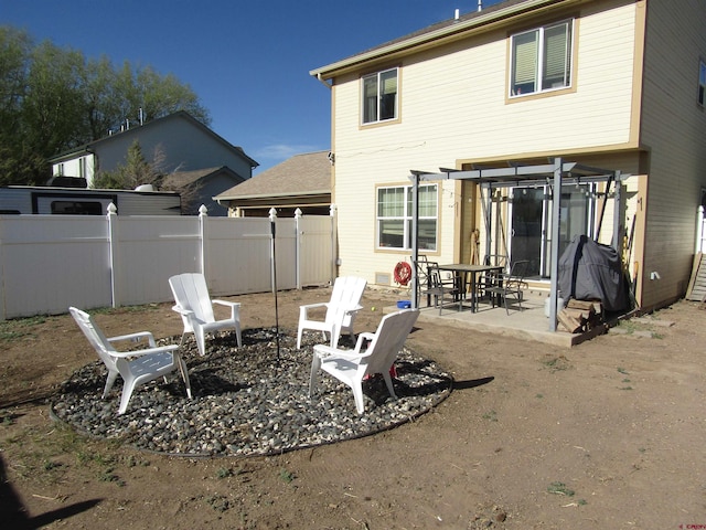 rear view of property featuring fence, a patio, a pergola, and a fire pit