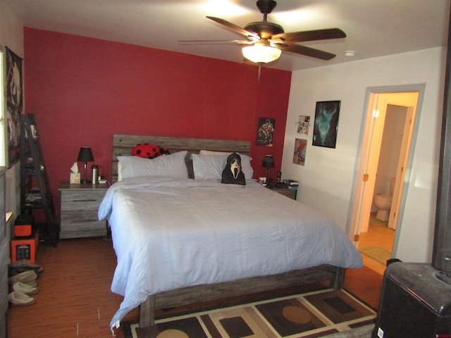 bedroom featuring ensuite bath, wood finished floors, and a ceiling fan