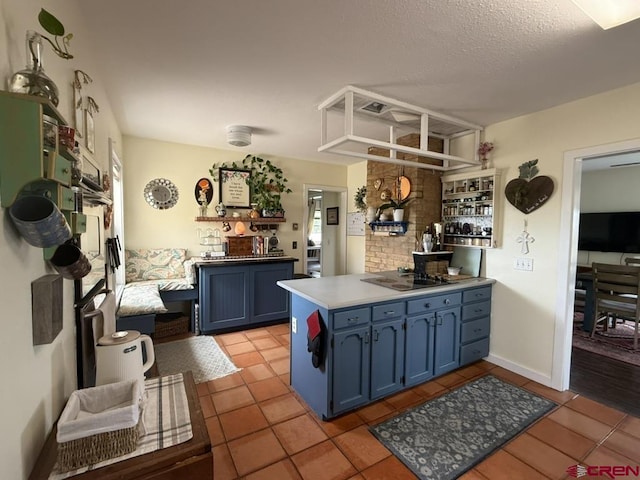 15556 D Rd, Delta, CO 81416 - kitchen featuring blue cabinetry, light tile patterned floors, a peninsula, black electric stovetop, and a textured ceiling