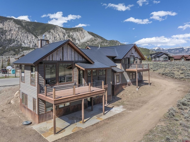 70 Lexie Ct, Crested Butte, CO 81224 - back of house featuring metal roof, a standing seam roof, a deck with mountain view, and a chimney