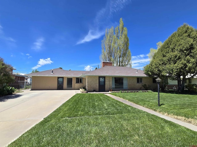 single story home with a chimney, a front lawn, brick siding, and driveway