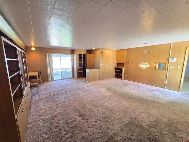 unfurnished living room with carpet floors and wooden walls