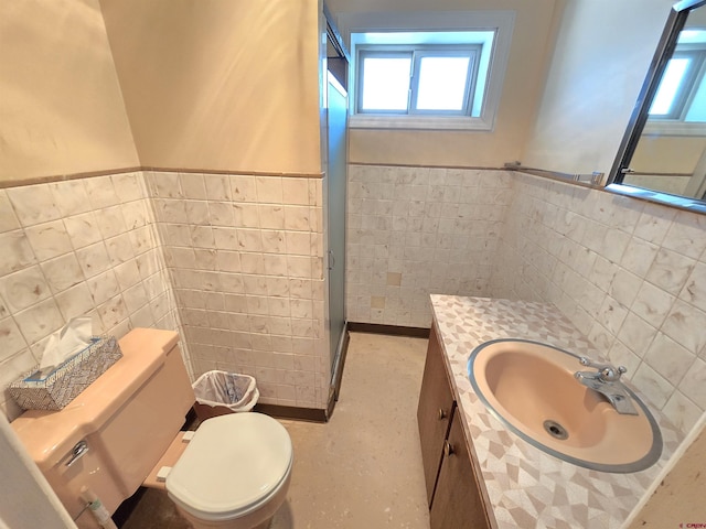 bathroom featuring tile walls, healthy amount of natural light, a wainscoted wall, toilet, and vanity