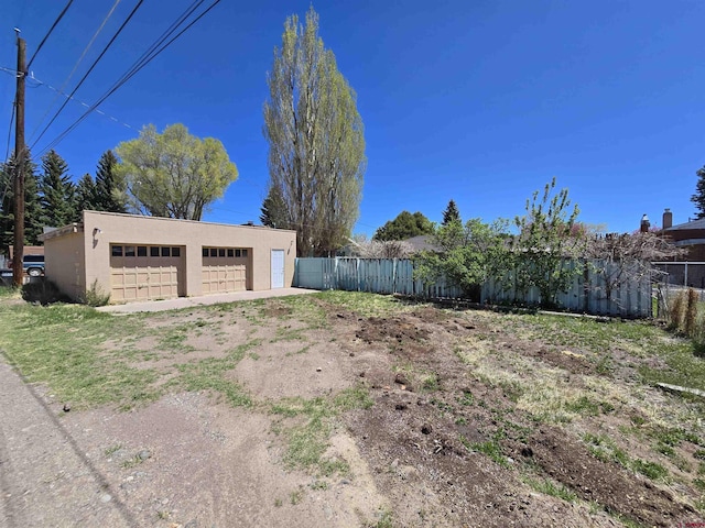 view of yard with fence, a garage, and an outbuilding