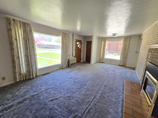 unfurnished living room with a fireplace, a textured ceiling, carpet floors, and baseboards