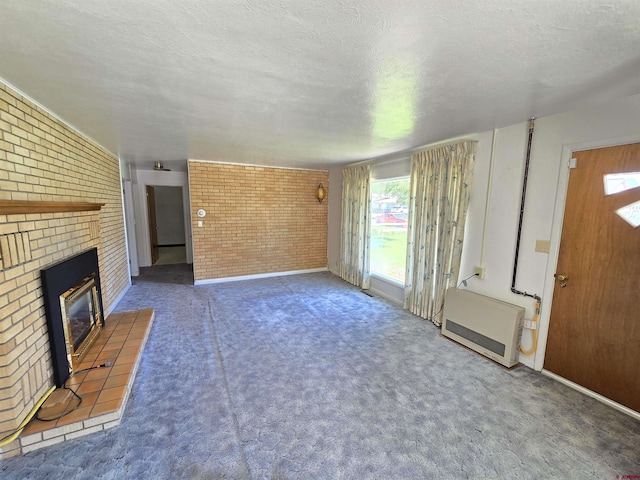 unfurnished living room featuring brick wall, healthy amount of natural light, a brick fireplace, carpet flooring, and a textured ceiling