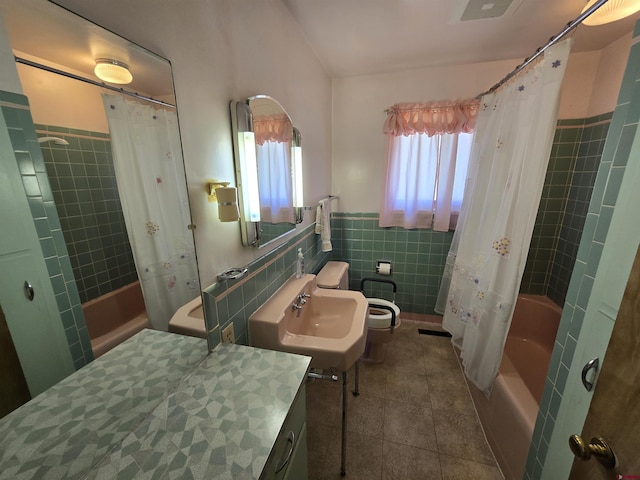 bathroom featuring tile walls, shower / bathtub combination with curtain, a sink, a wainscoted wall, and tile patterned flooring