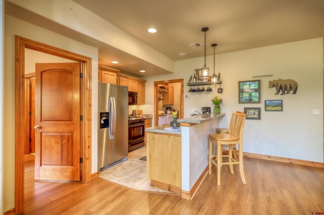 135 Eaton Dr Unit 1012, Pagosa Springs, CO 81147 - kitchen with stainless steel fridge with ice dispenser, range with gas cooktop, black microwave, a peninsula, and a kitchen bar