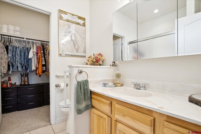 502 S Juniper Pl, Cortez, CO 81321 - bathroom featuring vanity, toilet, tile patterned floors, and a spacious closet