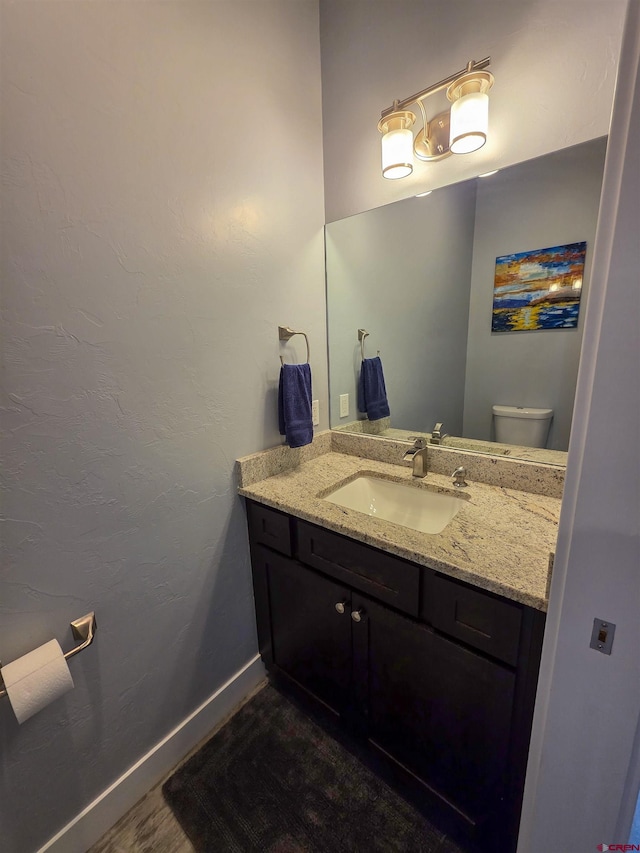 1771 Trappers Ct, Delta, CO 81416 - half bathroom featuring vanity, toilet, wood finished floors, and baseboards