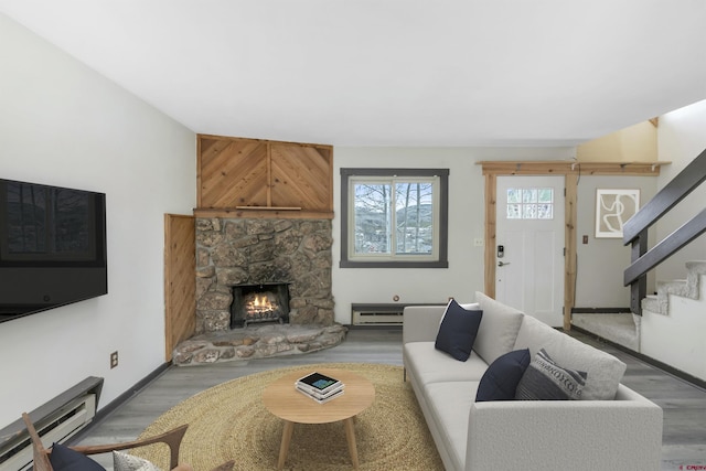 22 Castle Rd Unit 2, Mount Crested Butte, CO 81225 - living room with baseboard heating, stairs, wood finished floors, a stone fireplace, and baseboards