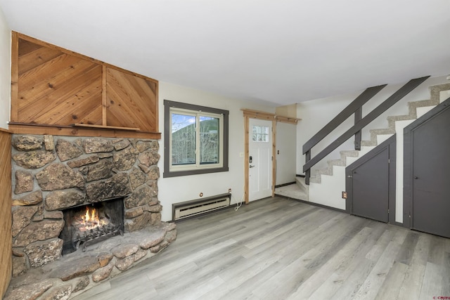 22 Castle Rd Unit 2, Mount Crested Butte, CO 81225 - unfurnished living room featuring a baseboard heating unit, stairs, light wood-style floors, and a stone fireplace