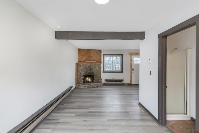 22 Castle Rd Unit 2, Mount Crested Butte, CO 81225 - unfurnished living room featuring baseboard heating, beamed ceiling, a baseboard radiator, light wood finished floors, and a fireplace