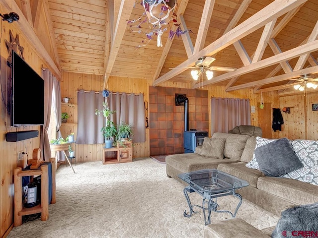 living area with a wood stove, wooden walls, wood ceiling, ceiling fan, and carpet flooring