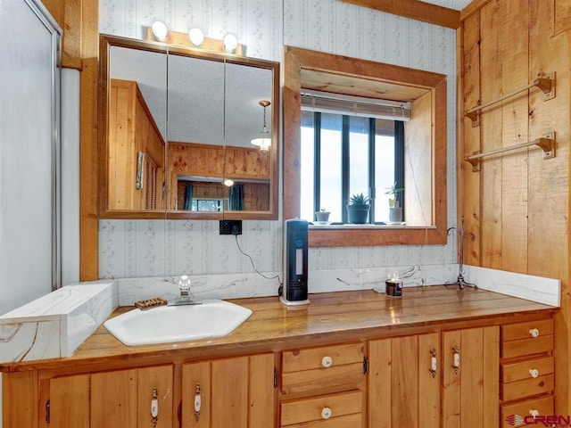 bathroom with wallpapered walls and vanity