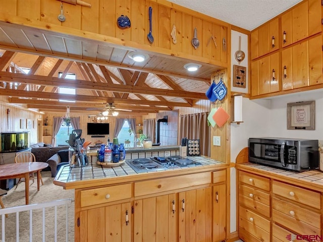 kitchen featuring tile countertops, stainless steel electric cooktop, ceiling fan, open floor plan, and lofted ceiling