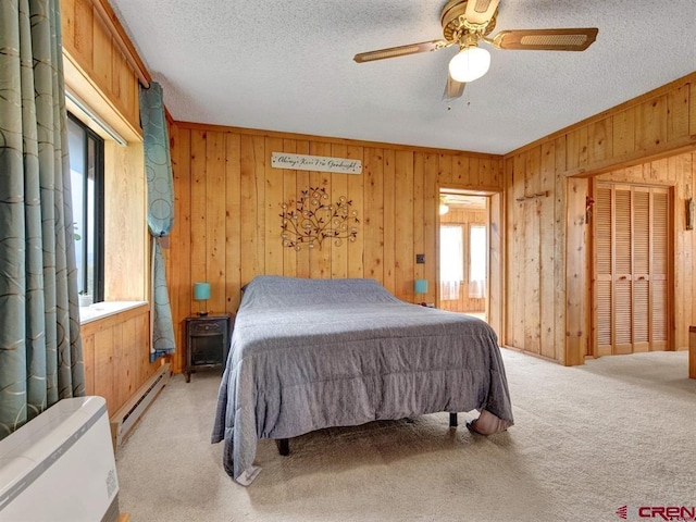 bedroom featuring a baseboard radiator, wooden walls, a textured ceiling, light carpet, and ceiling fan