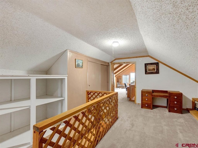 hall with a textured ceiling, lofted ceiling, and carpet