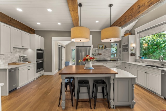 414 N Spruce St, Gunnison, CO 81230 - kitchen with a sink, stainless steel appliances, decorative backsplash, white cabinets, and beamed ceiling