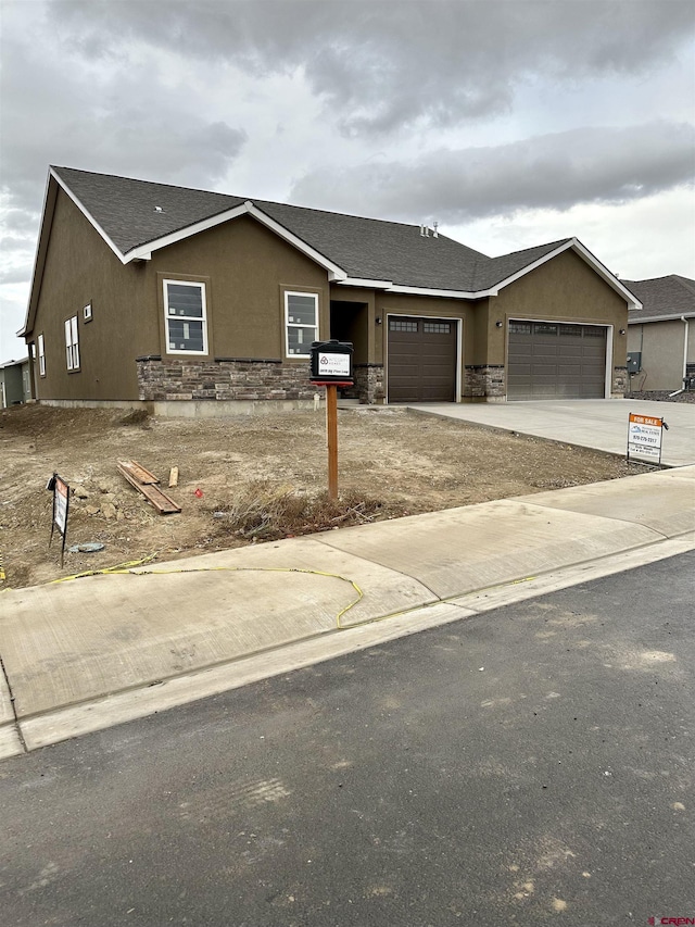 LOT66 6429th Cir, Montrose, CO 81403 - view of front of house with an attached garage, stone siding, stucco siding, concrete driveway, and roof with shingles