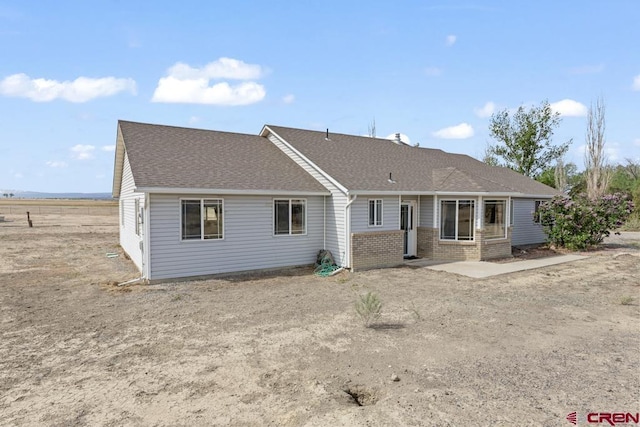 19496 E Rd, Delta, CO 81416 - rear view of house featuring brick siding, a shingled roof, and a patio area