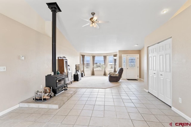 19496 E Rd, Delta, CO 81416 - living room featuring a wood stove, a ceiling fan, light tile patterned floors, vaulted ceiling, and baseboards