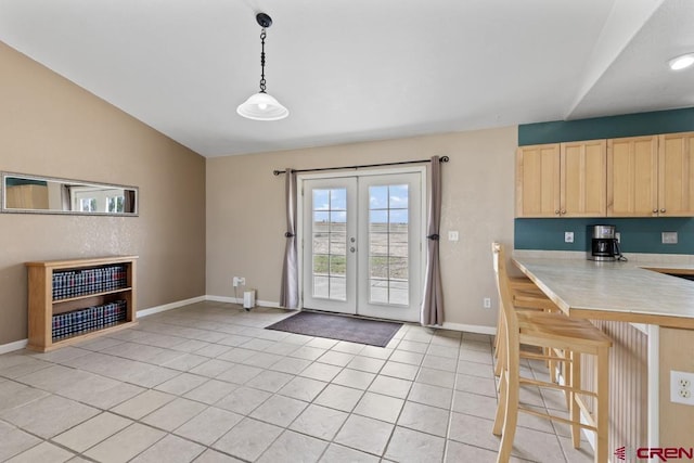 19496 E Rd, Delta, CO 81416 - kitchen featuring light brown cabinetry, light countertops, light tile patterned floors, french doors, and a kitchen breakfast bar