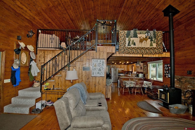 living room with a wood stove, wood walls, stairway, hardwood / wood-style floors, and wood ceiling