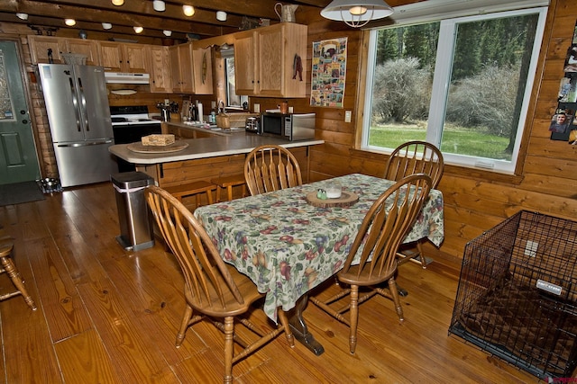 dining room featuring plenty of natural light, dark wood finished floors, and wooden walls