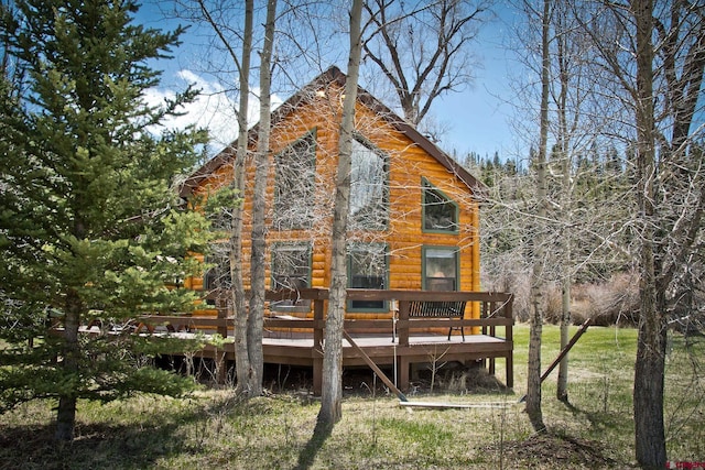 rear view of house with a wooden deck and a lawn