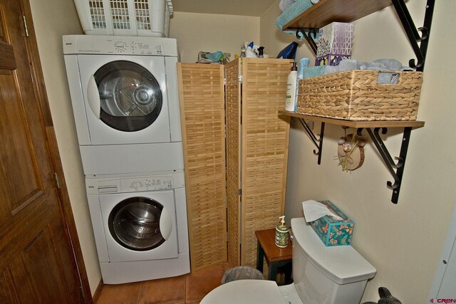washroom featuring stacked washer and clothes dryer and tile patterned flooring