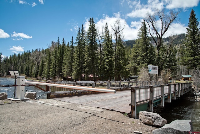 dock area featuring a boat ramp, a forest view, and a water view