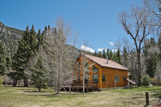 view of side of home with a yard, a wooden deck, and metal roof