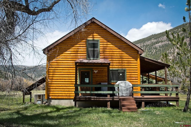 view of front of house with a deck with mountain view and a front lawn