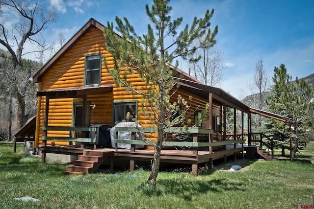 back of property featuring a wooden deck and a lawn