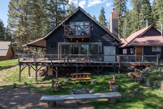 back of house with a chimney, a wooden deck, and a lawn