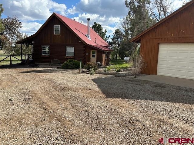 21330 Rd V.6, Lewis, CO 81327 - view of side of home with a garage, metal roof, and driveway