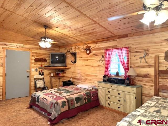 12427 Rd G, Cortez, CO 81321 - bedroom with wood ceiling, wood walls, and carpet flooring