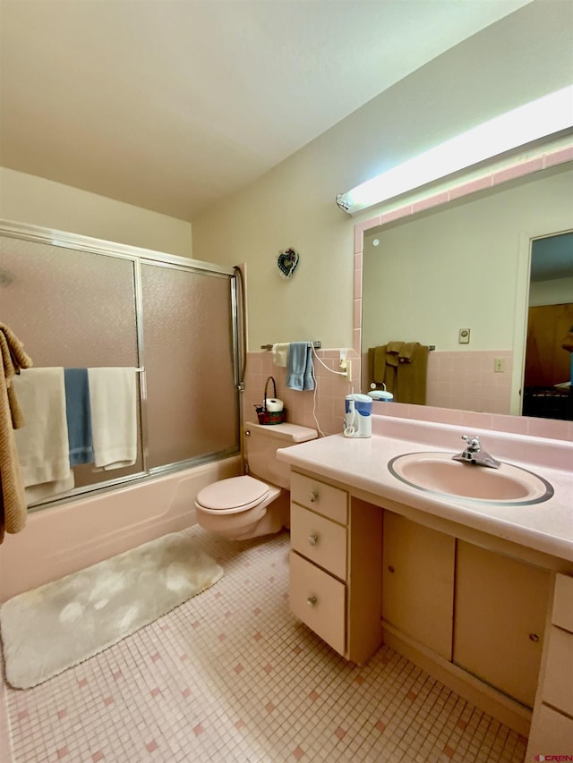 622 Rio Vista Rd, Gunnison, CO 81230 - bathroom featuring vanity, shower / bath combination with glass door, toilet, tile walls, and tile patterned flooring