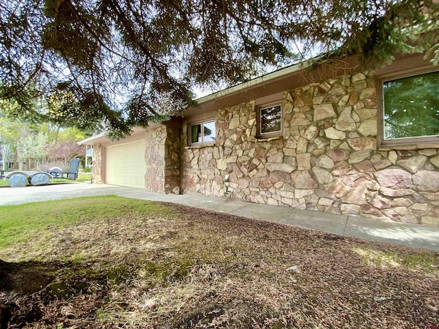 622 Rio Vista Rd, Gunnison, CO 81230 - view of property exterior with stone siding, an attached garage, and concrete driveway