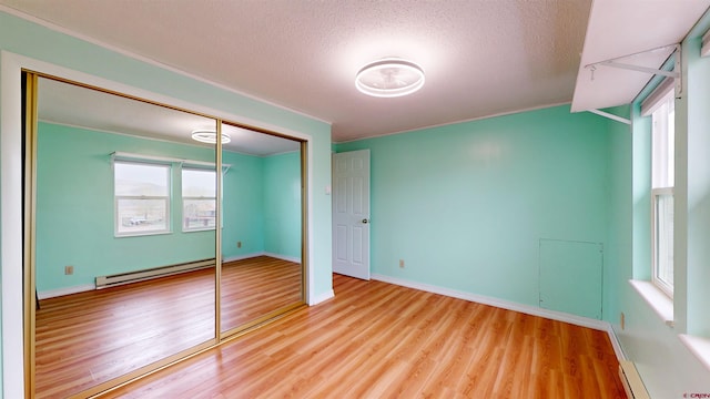 15 Tomichi Ln, Gunnison, CO 81230 - unfurnished bedroom featuring a baseboard radiator, wood finished floors, a textured ceiling, a closet, and baseboards