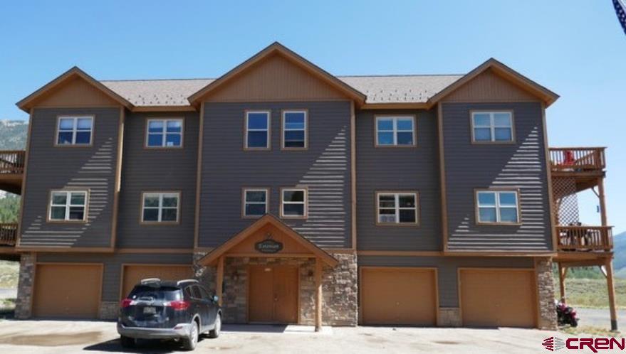 25 Elk Valley Rd Unit 202, Crested Butte, CO 81224 - townhome / multi-family property with an attached garage, stone siding, driveway, and a deck