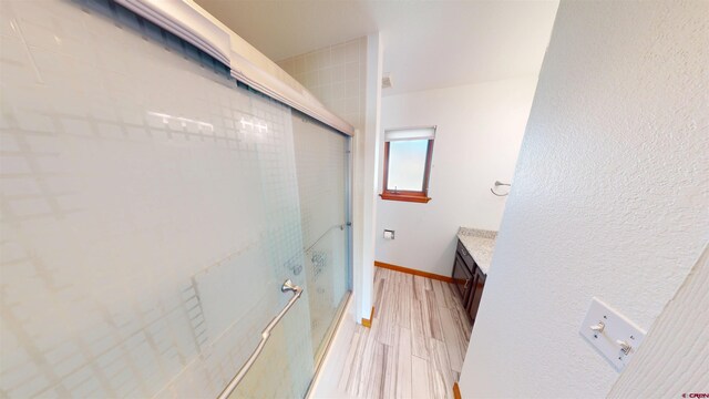 15 Sunnybrook Pl, Alamosa, CO 81101 - bathroom featuring a shower with door, wood finished floors, vanity, and baseboards